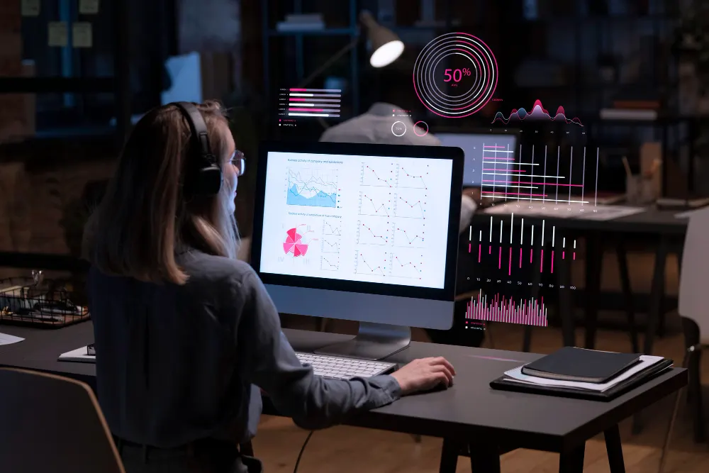 A professional reviewing charts at a desktop computer, with data visualizations overlaid